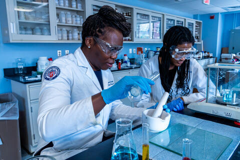 photo of two people working a pharmacy compounding lab 